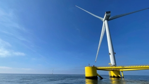 Floating wind turbine on a yellow semi-submersible base with another turbine visible in the distance