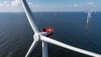 Aerial view of an offshore wind farm with a close-up turbine nacelle and rows of turbines across open sea